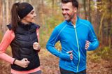 Twee mensen joggen samen over een bospad.